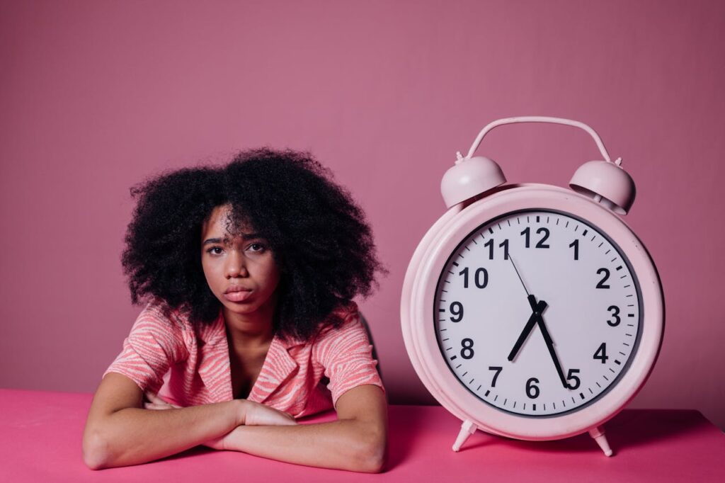 Femme pensive, anxieuse, avec une horloge à coté, symbole du temps qui passe - procrastination - psychothérapie Paris 9