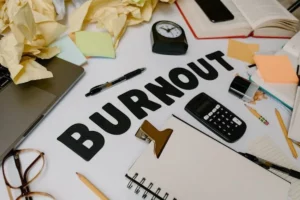 papiers réparties de manière aléatoire sur un bureau avec marqué en lettres capitales burn out - psychopraticien Paris 9