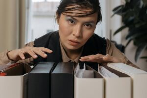 Femme désespérée qui nous regarde alors qu'elle a les mains posées sur des classeurs - phobie administrative - psychothérapie Paris 9