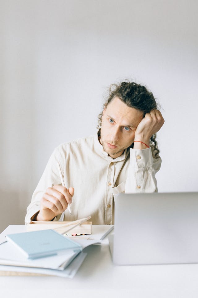 Homme anxieux assis à son bureau devant son bureau, ordinateur et ses papiers - phobie administrative - psychothérapie Paris 9