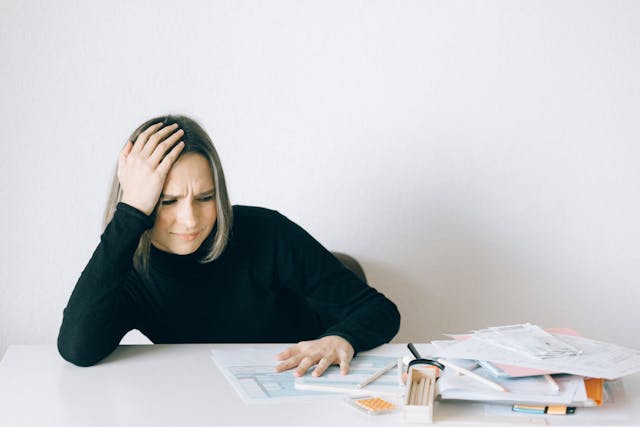 Femme anxieuse, le coude sur la table, la main sur la tête, devant des papiers - phobie administrative - psychothérapie à Paris 9