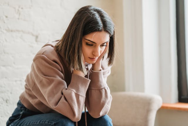 Jeune femme les mains sur ses tempes, pensive - dépression - Psychopraticien Paris 9