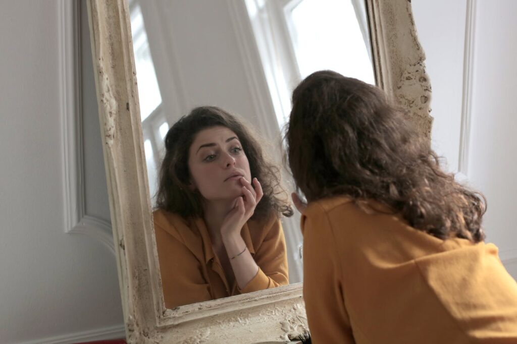 femme qui se regarde dans le miroir, pensive - dysmorphophobie - psychothérapie paris 9