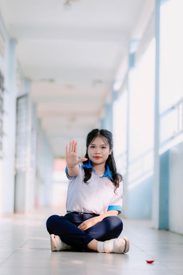Une élève assise par terre qui fait un signe stop de la main - harcèlement scolaire - Psychothérapie systémique palo alto Paris 9