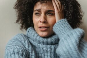 Femme qui pleure, la main sur tempe, triste - hypersensibilité - psychothérapie à Paris 9