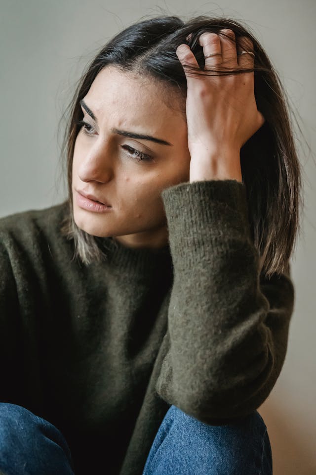 Femme pensive, la main sur la tête - hypersensibilité - psychothérapie Paris 9