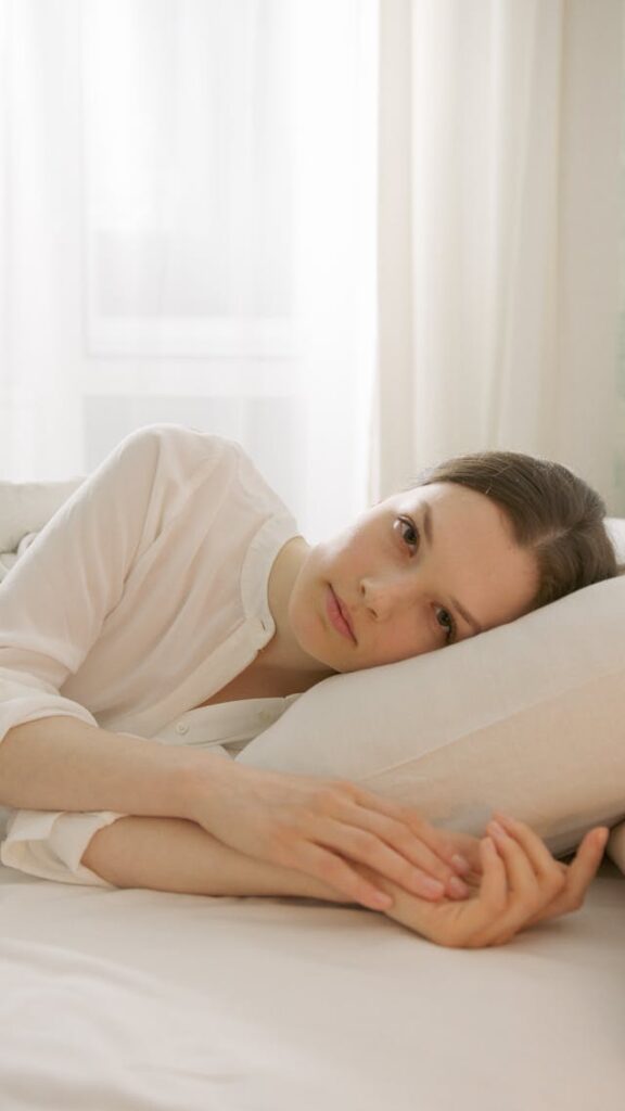 Femme allongée sur le lit dont on voit le visage triste et pensif - syndrome de l'imposteur - psychothérapie Paris 9