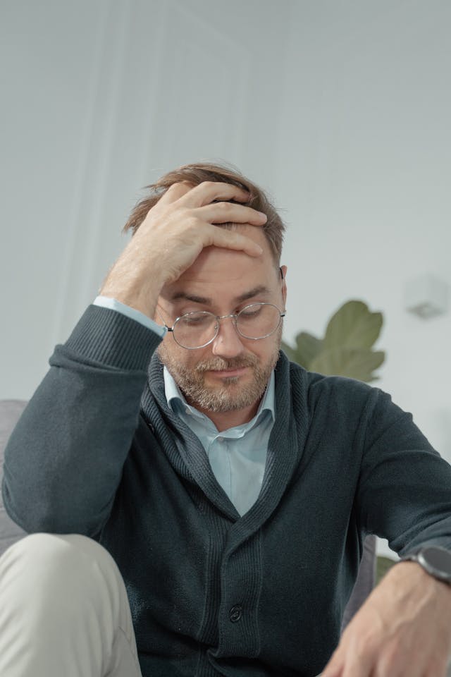 Homme pensif et anxieux, la main posée sur sa tête - Trouble anxieux généralisé (TAG) - Psychothérapie Paris 9