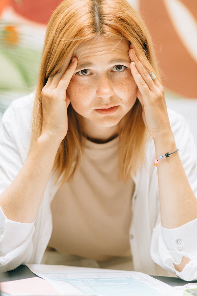 Femme pensive, anxieuse, les mains sur les tempes - trouble anxieux généralisé (TAG) - psychothérapie Paris 9