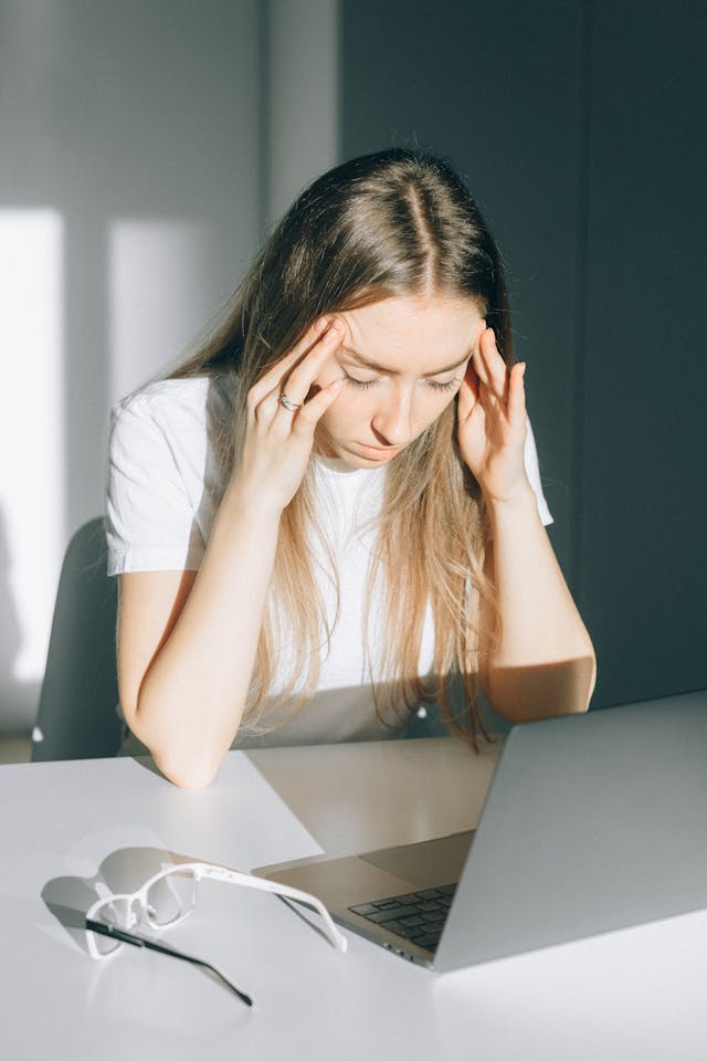 Femme qui semble épuisée, les mains sur les tempes - charge mentale - psychothérapie Paris 9