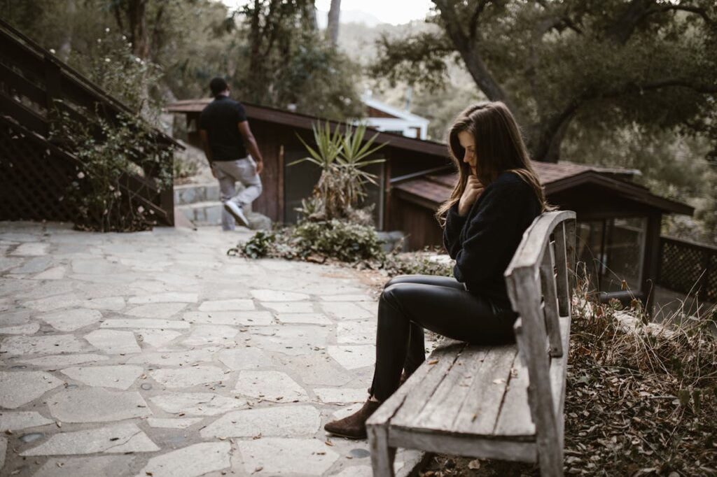 Femme pensive et triste sur un banc alors que son ex compagnon s'éloigne - rupture amoureuse - Psychothérapie Paris 9 