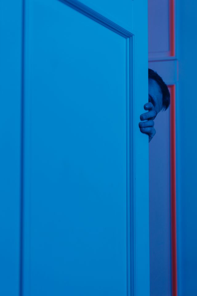 Une personne ouvre la porte mais se cache derrière cette même porte - claustrophobie - psychothérapie Paris