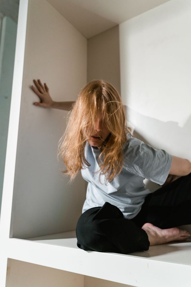 Femme en position artistique la main sur un des murs de l'espace dans laquelle elle se trouve - claustrophobie - psychothérapie Paris