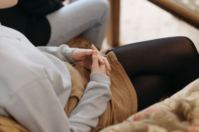 Femme assise sur un canapé, les mains croisées - alexithymie - psychothérapie Paris