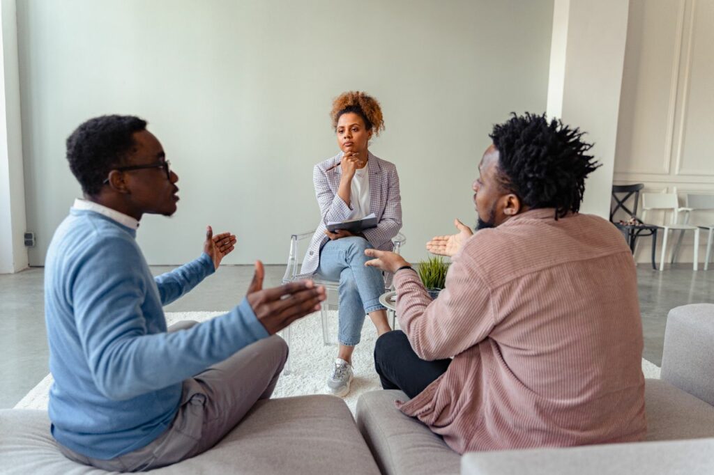 Deux hommes échangent en faisant des gestes avec les mains devant une thérapeute - sur-responsabilité et sur-adaptabilité - psychothérapie Paris 9