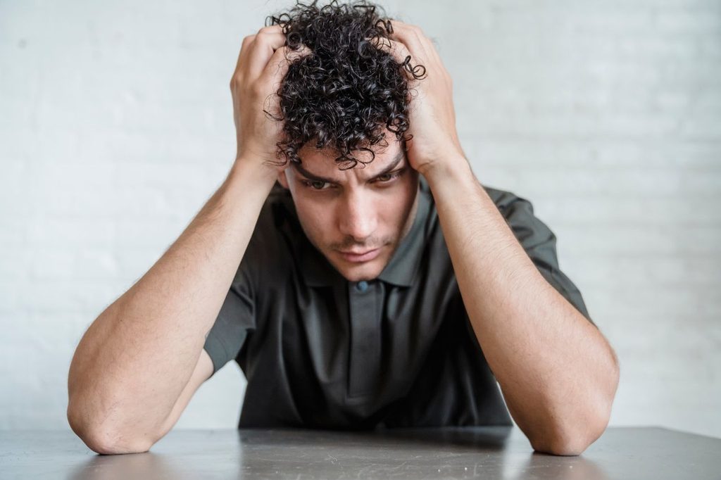 Homme assis, les mains sur les tempes, pensif - Rumination mentale - psychothérapie Paris 9
