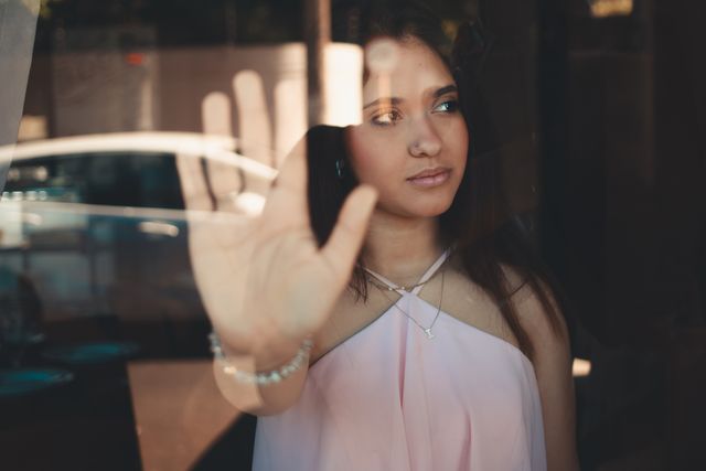 Une femme, le regard porté sur sa gauche, pose la main devant elle, supposément sur une vitre - auto-sabotage - Psychothérapie Paris 9 et Pantin