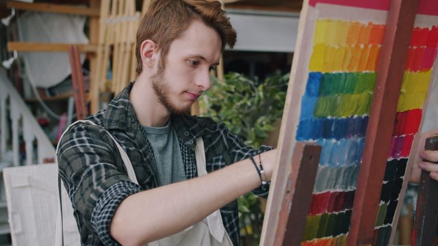 Jeune homme, qui fait de la peinture, concentré sur sa toile - TSA (Trouble du Spectre de l'Autisme) - Psychothérapie Paris 9 et Pantin