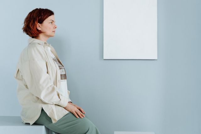 Femme assise, le regard fixe dans une pièce avec au mur un tableau blanc - TSA (Trouble du Spectre de l'Autisme) - Psychothérapie Paris 9 et Pantin