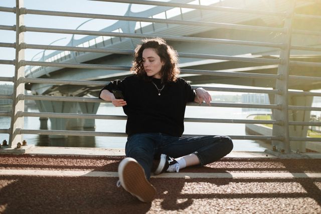 Femme assise de façon décontractée au sol sur un pont, pensive - TSA (Trouble du Spectre de l'Autisme) - Psychothérapie Paris 9 et Pantin